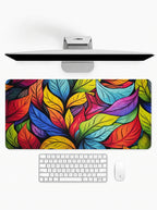 Stained Glass Flora deskmat featuring colorful botanical leaf artwork and stitched edges